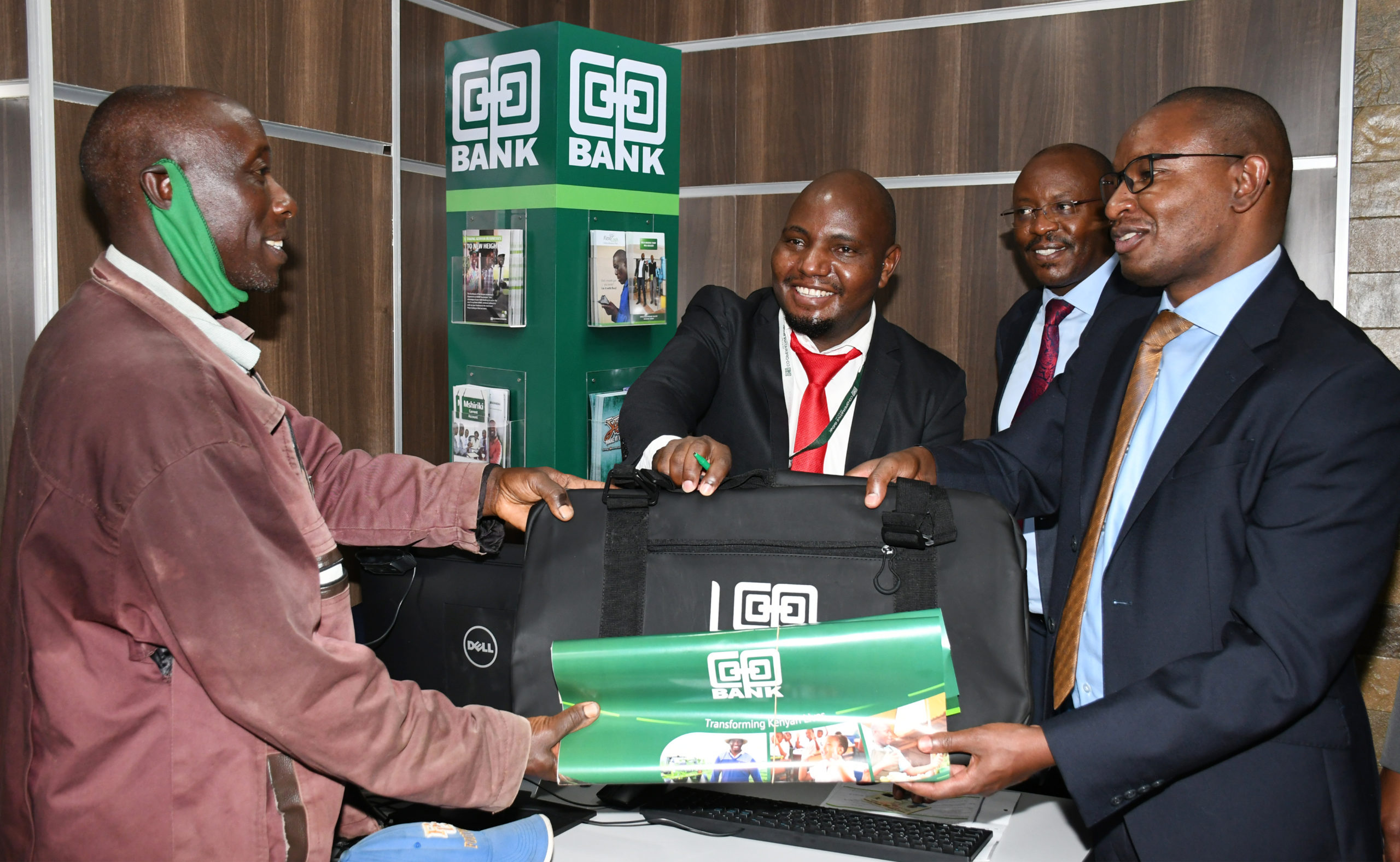 Director Retail & Business Banking William Ndumia presents a gift to Mr. who was the first client to open an account after the official opening of Co-op Kamulu branch Mr Joseph Kimathi Ndegwa . Looking on is the bank's Head of Branch Banking Peter Kirugu.