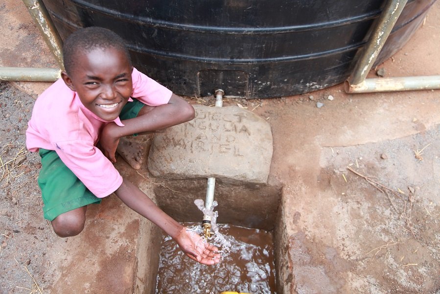 A pupil at Matangini Primary School enjoys the free flowing water from the water tank donated to the school by Airtel.