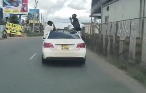 Two people were nabbed for hanging precariously from a speeding Mercedes.